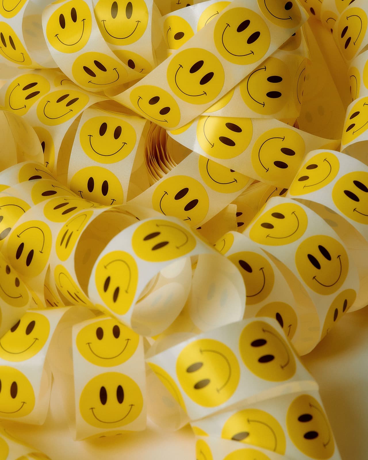 Tiras enroladas de adesivos redondos de carinha sorridente amontoadas umas sobre as outras